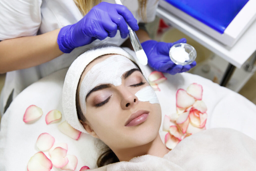 Cosmetologiest applies white mask on woman's face